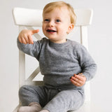 Toddler wearing heather grey cashmere pants while sitting on chair.