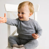 Toddler wearing a heather grey baby cashmere sweater sitting on a chair